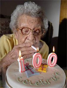Une femme allume sa cigarette avec les bougies de son gâteau d'anniversaire